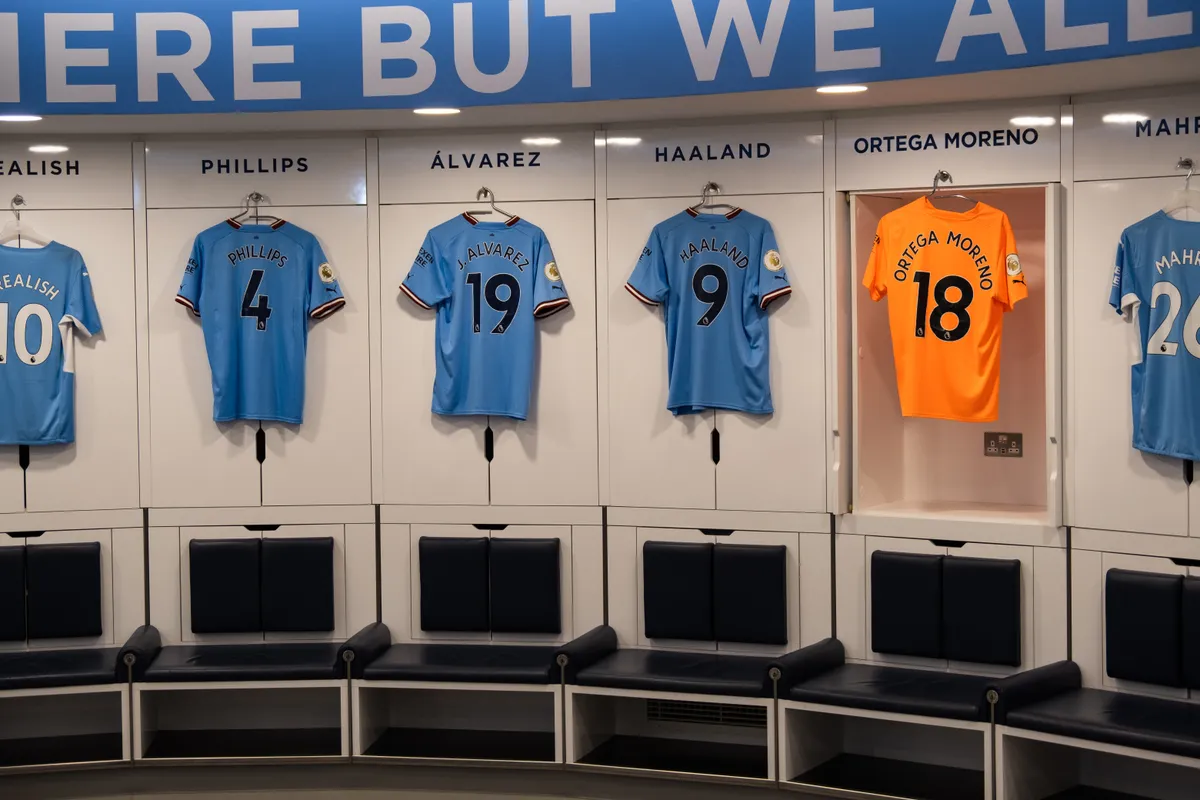 The Manchester City home dressing room with shirts hung above the seats, a stop on the Etihad stadium tour with kids