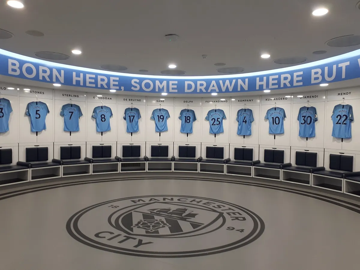 Real view of Manchester City circular home dressing room with shirts displayed above the seats